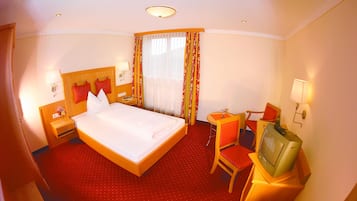 Ein Hotelzimmer mit einem großen Bett, einem Fernseher, einem Sessel und einem kleinen Tisch.