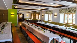A restaurant with long communal tables, benches, and a green accent wall. - Gasthof Messerschmied (Grassau)