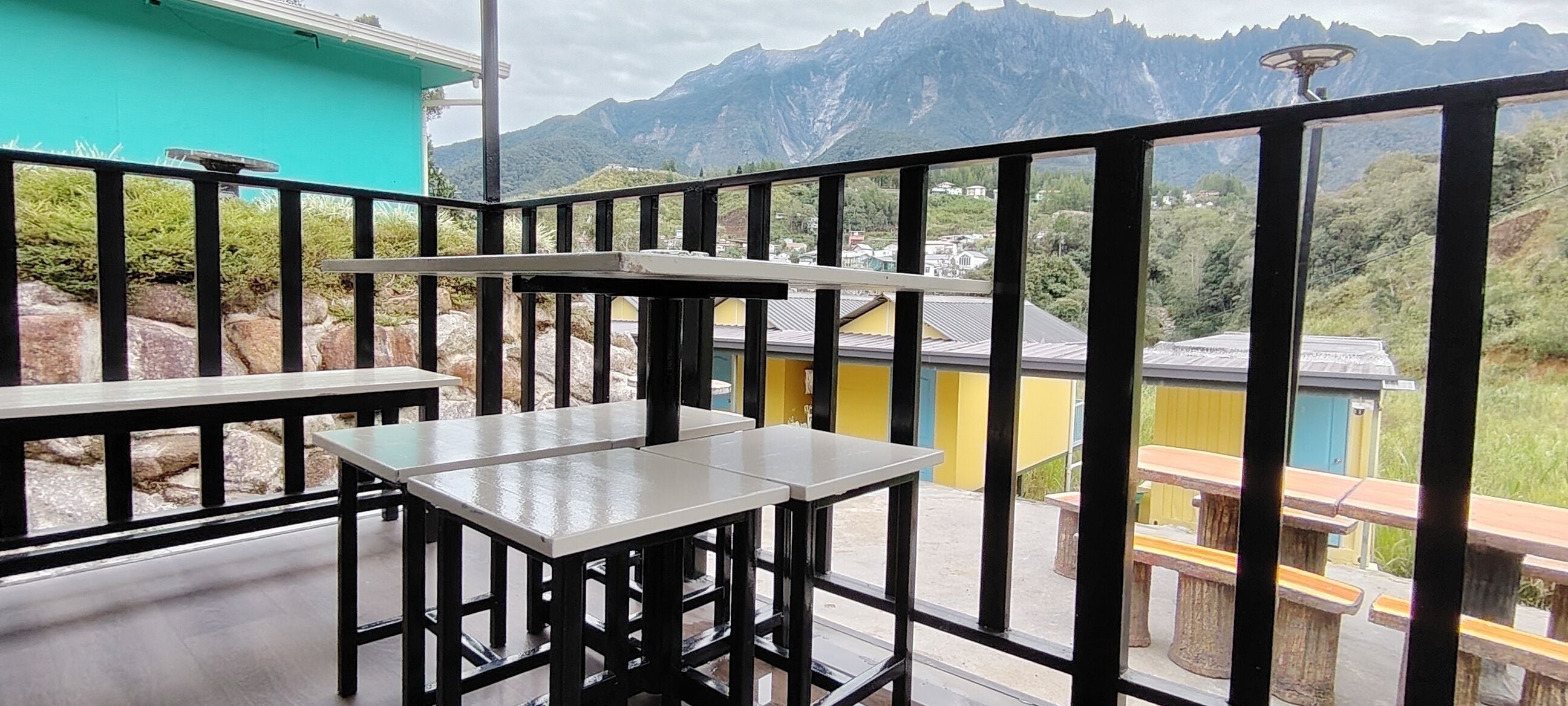 Un balcón con mesas y sillas, con vistas a un paisaje montañoso.