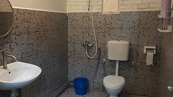 Un baño con lavamanos blanco, inodoro y ducha. El suelo presenta un diseño de mosaico.