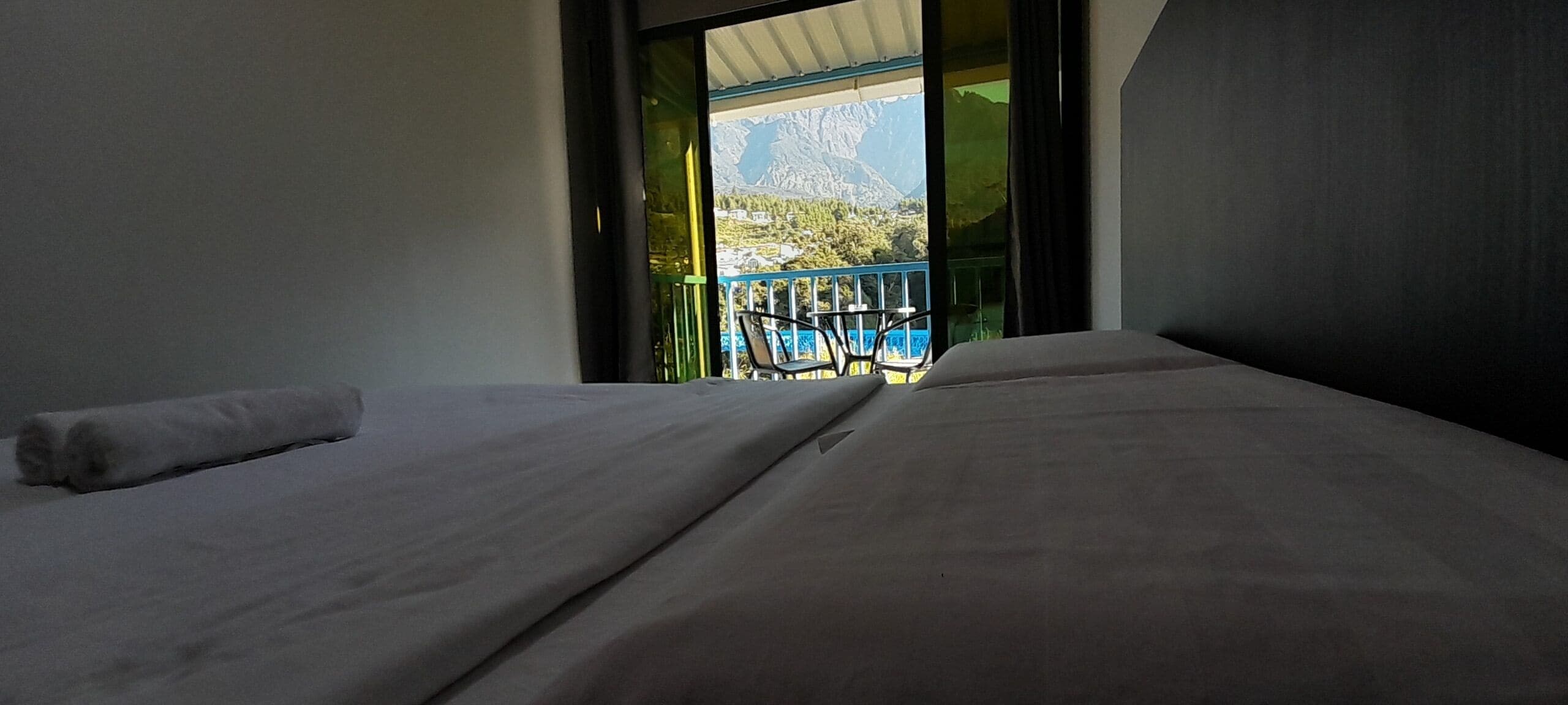 Habitació d'hotel amb dos llits i un balcó amb vista a la muntanya.