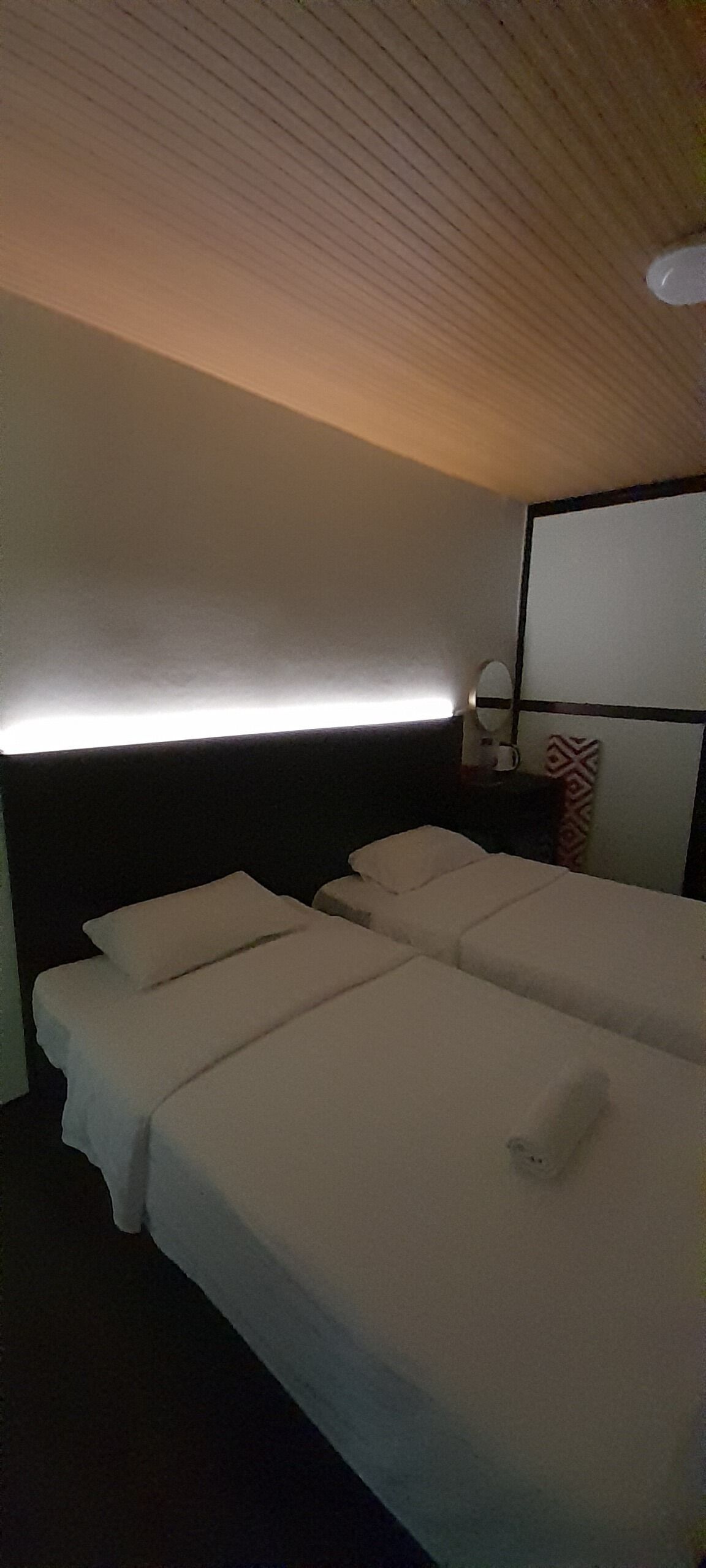 A hotel room with a large bed, a bedside table with a lamp, and a headboard with a mirror.