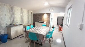 Una cocina compacta con estufa integrada, un lavamanos y una zona de comedor con mesa y sillas.