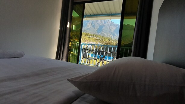 Habitación de hotel con cama, almohada y balcón con vistas a la montaña.