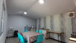 Una cocina compacta con salpicadero de mármol, un comedor con mesa y sillas, y un refrigerador pequeño.