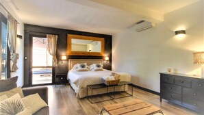 A modern bedroom with a large bed, a wooden headboard, a nightstand, a dresser, and a small table. - Chambre d'Hote Casa Maredda (Albitreccia)