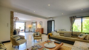 A spacious living room with a sofa, armchairs, and a coffee table. There is a dining area in the background with a table and chairs. - Chambre d'Hote Casa Maredda (Albitreccia)