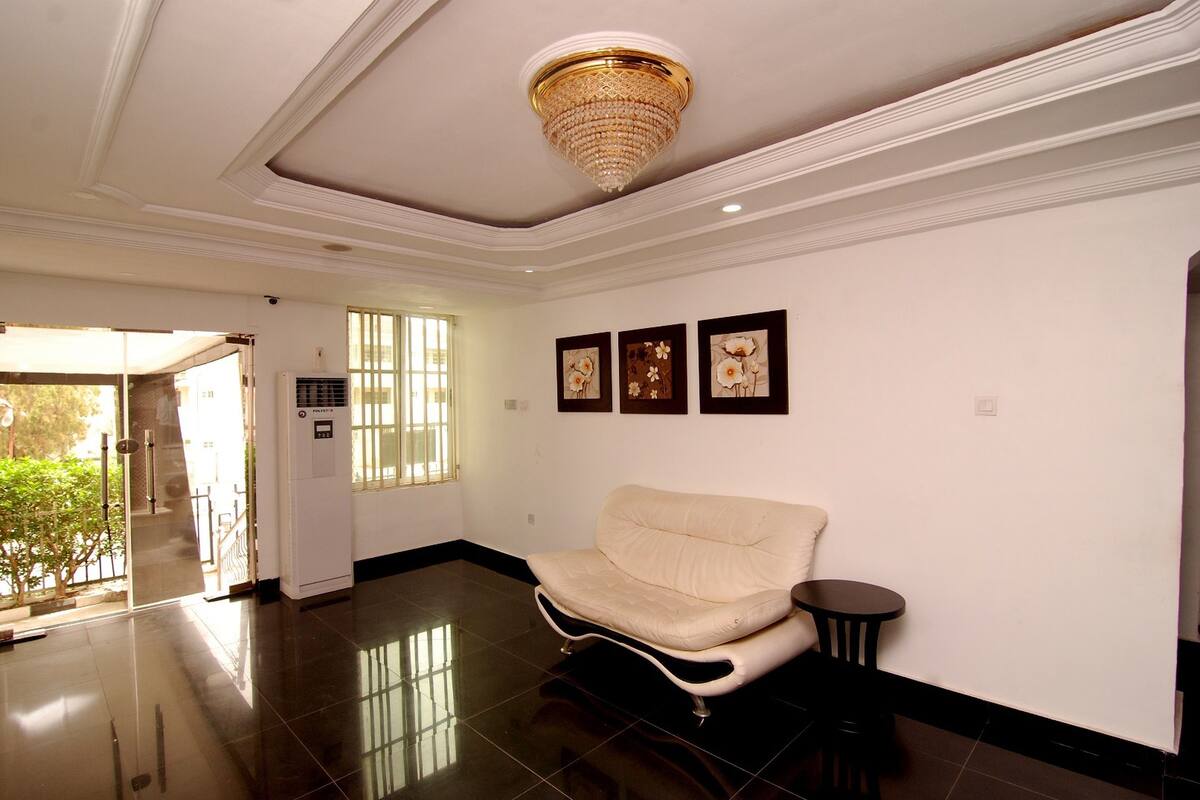 A spacious lobby with a cream-colored sofa, a small round table, and a chandelier.