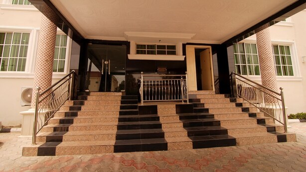 A staircase leading to an entrance with patterned columns and a metal railing. - Belvoir Hotel (Abuja)