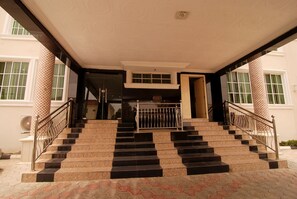 A staircase leading to an entrance with patterned columns and a metal railing. - Belvoir Hotel (Abuja)