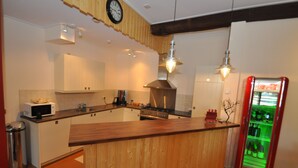 Una cocina moderna con armarios de madera, estufa de acero inoxidable, microondas y refrigerador con luz verde.