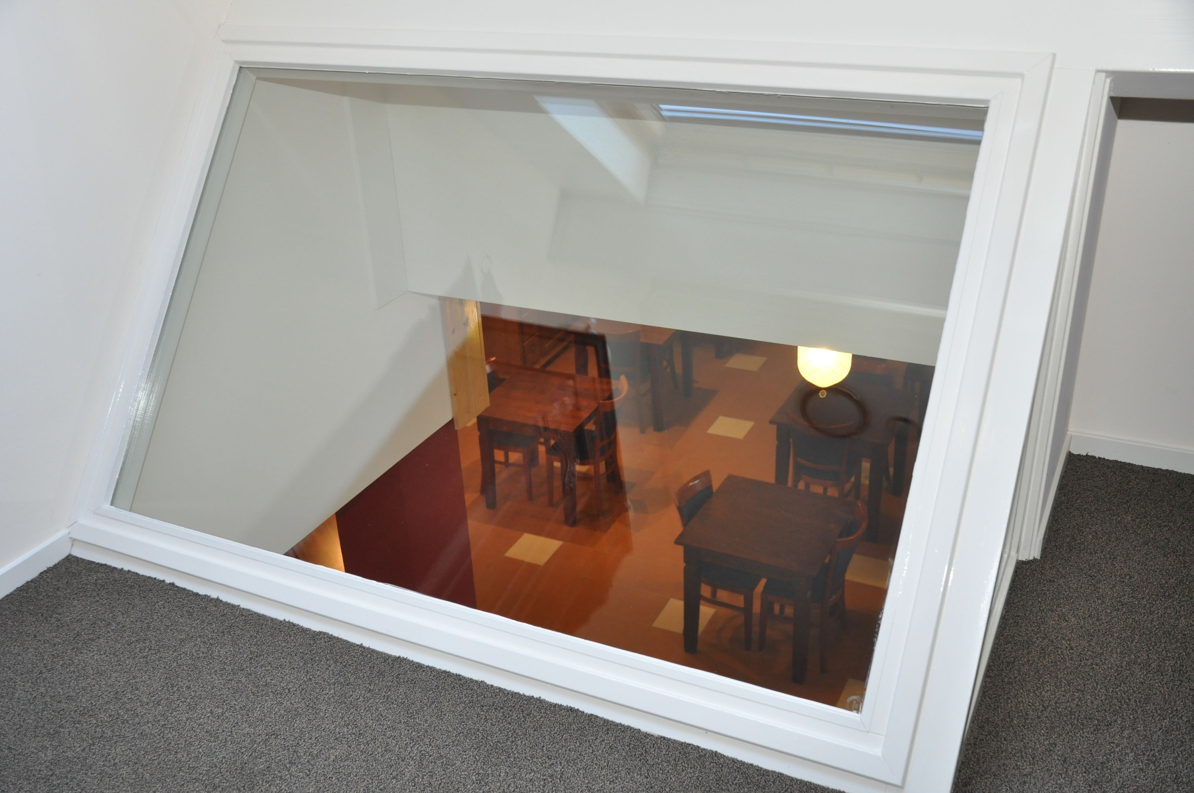 Una habitación con techo inclinado y puerta de cristal que da a un comedor con mobiliario de madera.