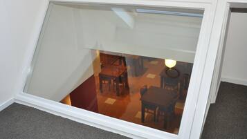 Una habitación con techo inclinado y puerta de cristal que da a un comedor con mobiliario de madera.