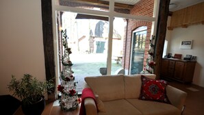 Una sala de estar con un sofá color beige, una planta en maceta y un árbol de Navidad.