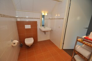 Un baño con inodoro, lavabo y toallero.