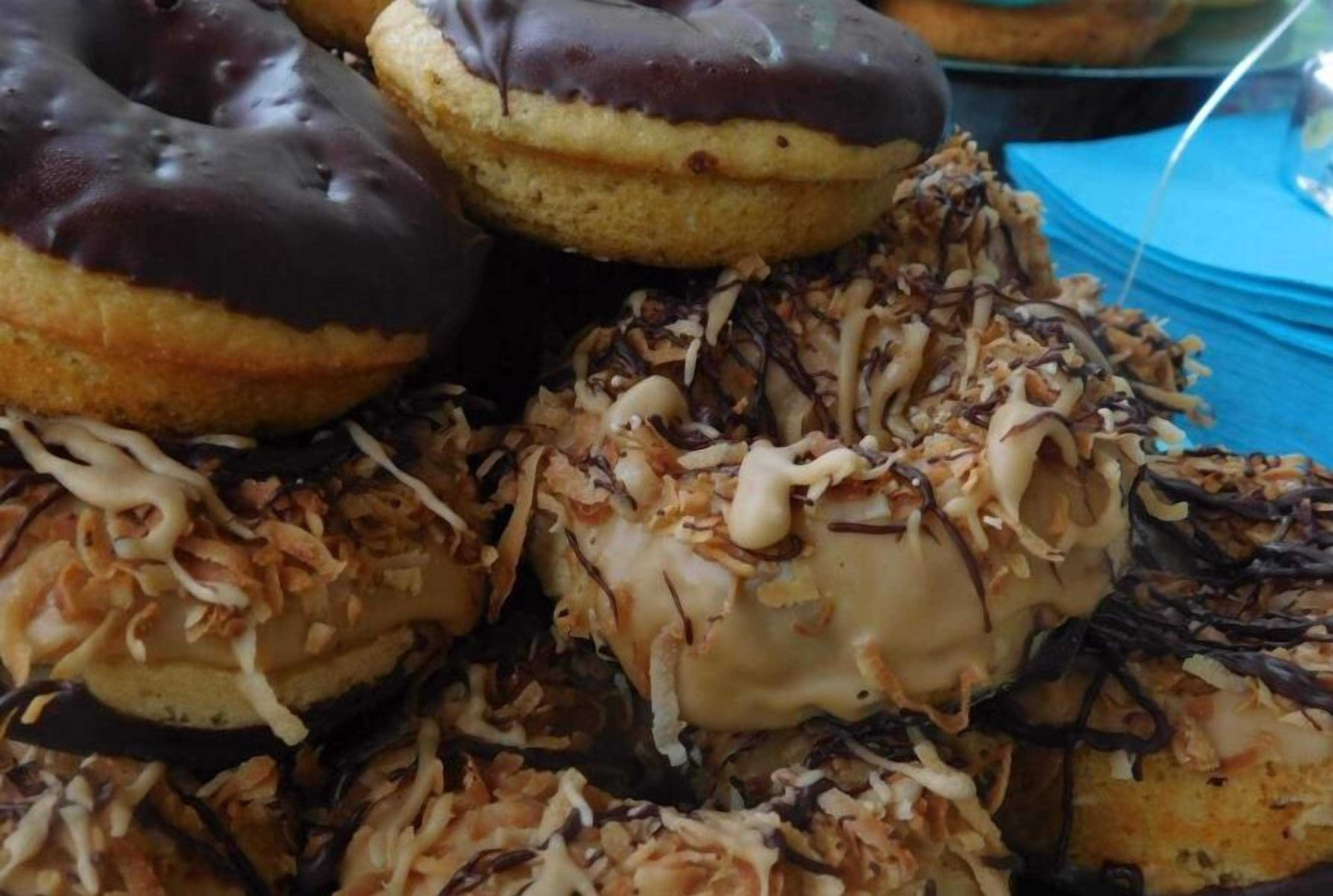 Un assortiment de beignets garnis de divers ingrédients, comme du chocolat et des copeaux de noix de coco.