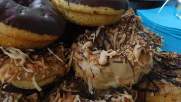 Un assortiment de beignets garnis de divers ingrédients, comme du chocolat et des copeaux de noix de coco.