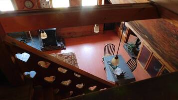 Interior de madera con zona de comedor, una escalera con detalles en forma de corazón y vistas a un reloj y una ventana.