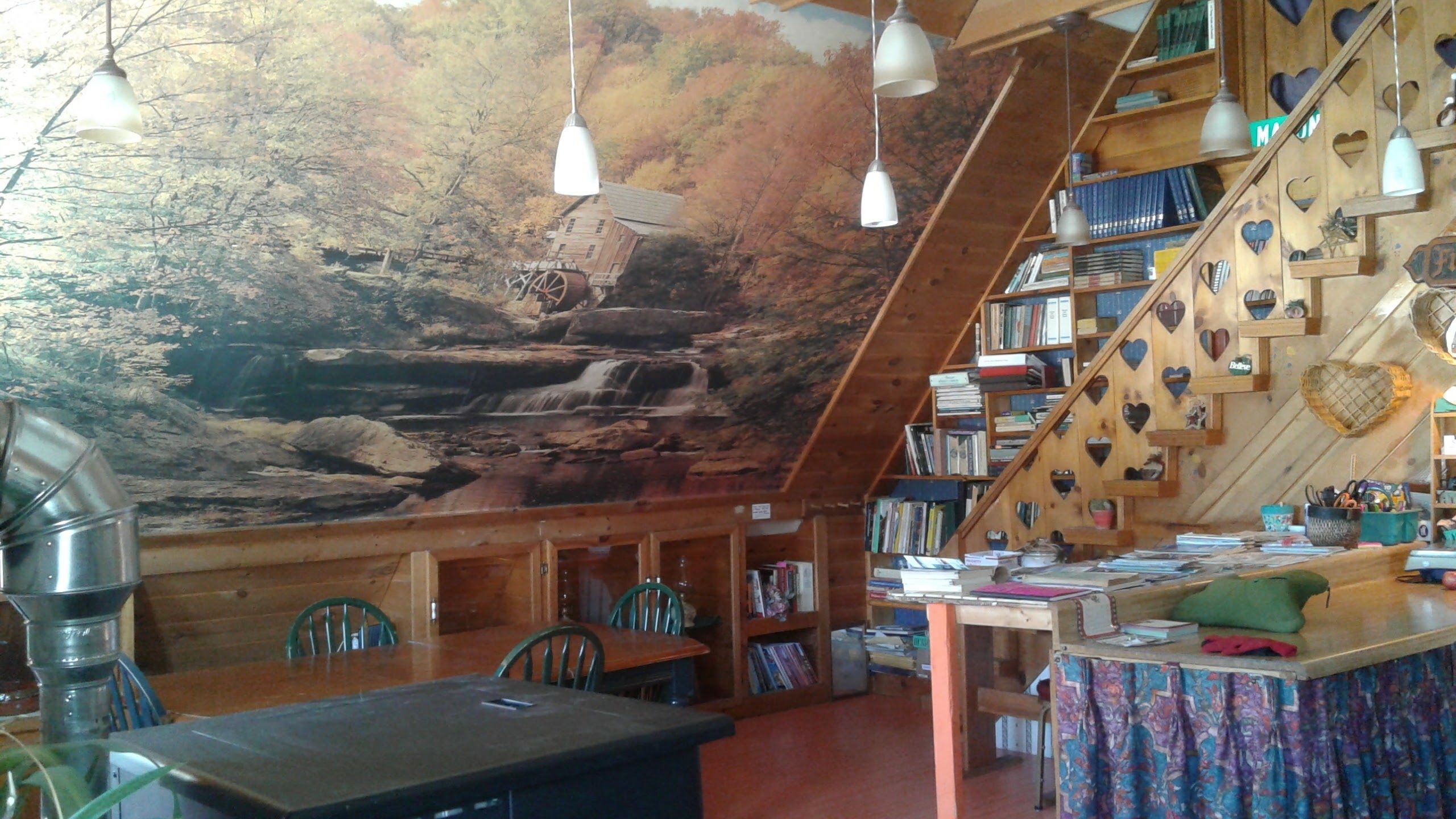 Un interior acogedor de cabaña con detalles rústicos de madera, una estantería y un comedor.