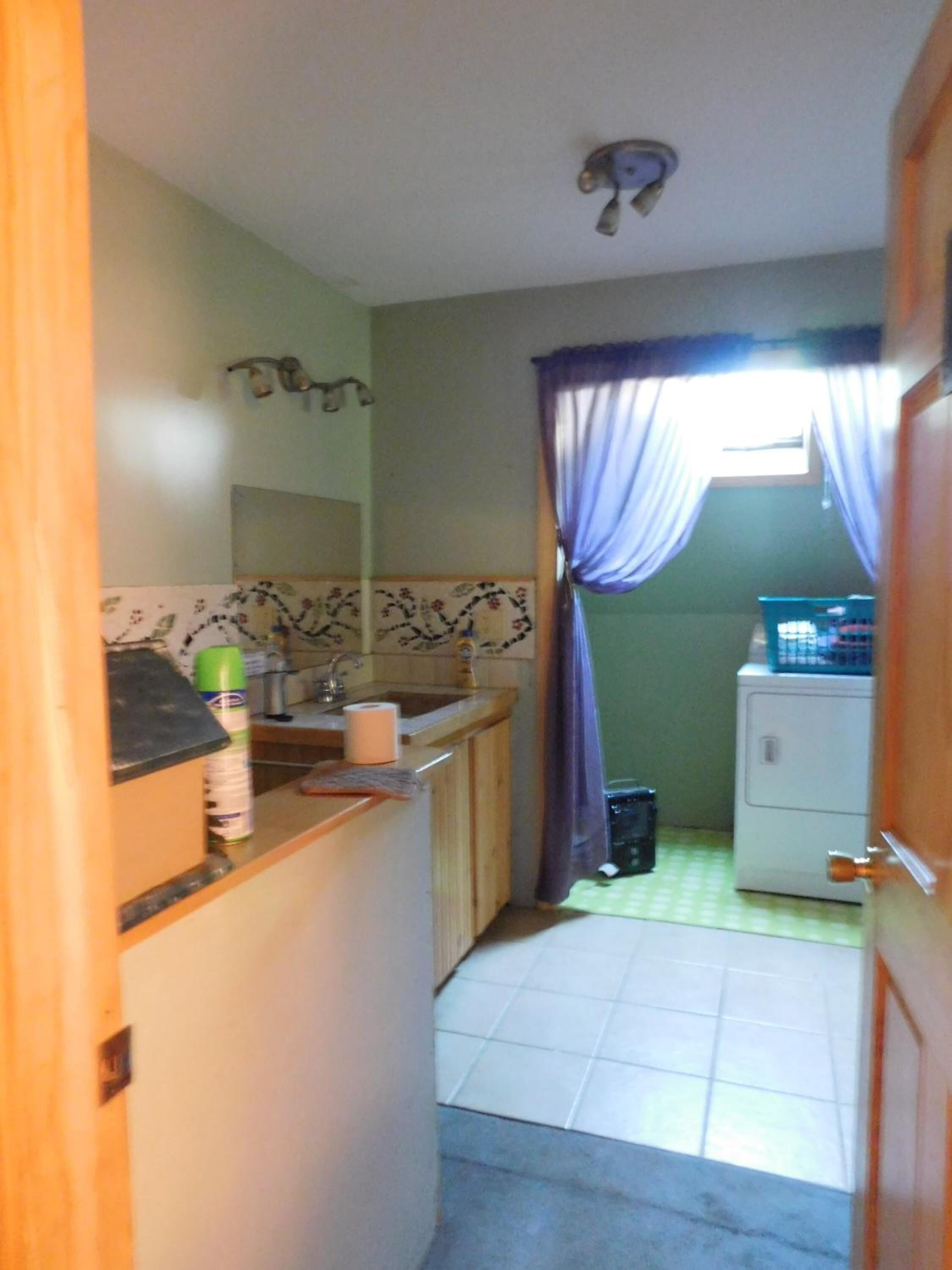 A small, compact kitchen with a sink, countertop, and a refrigerator.