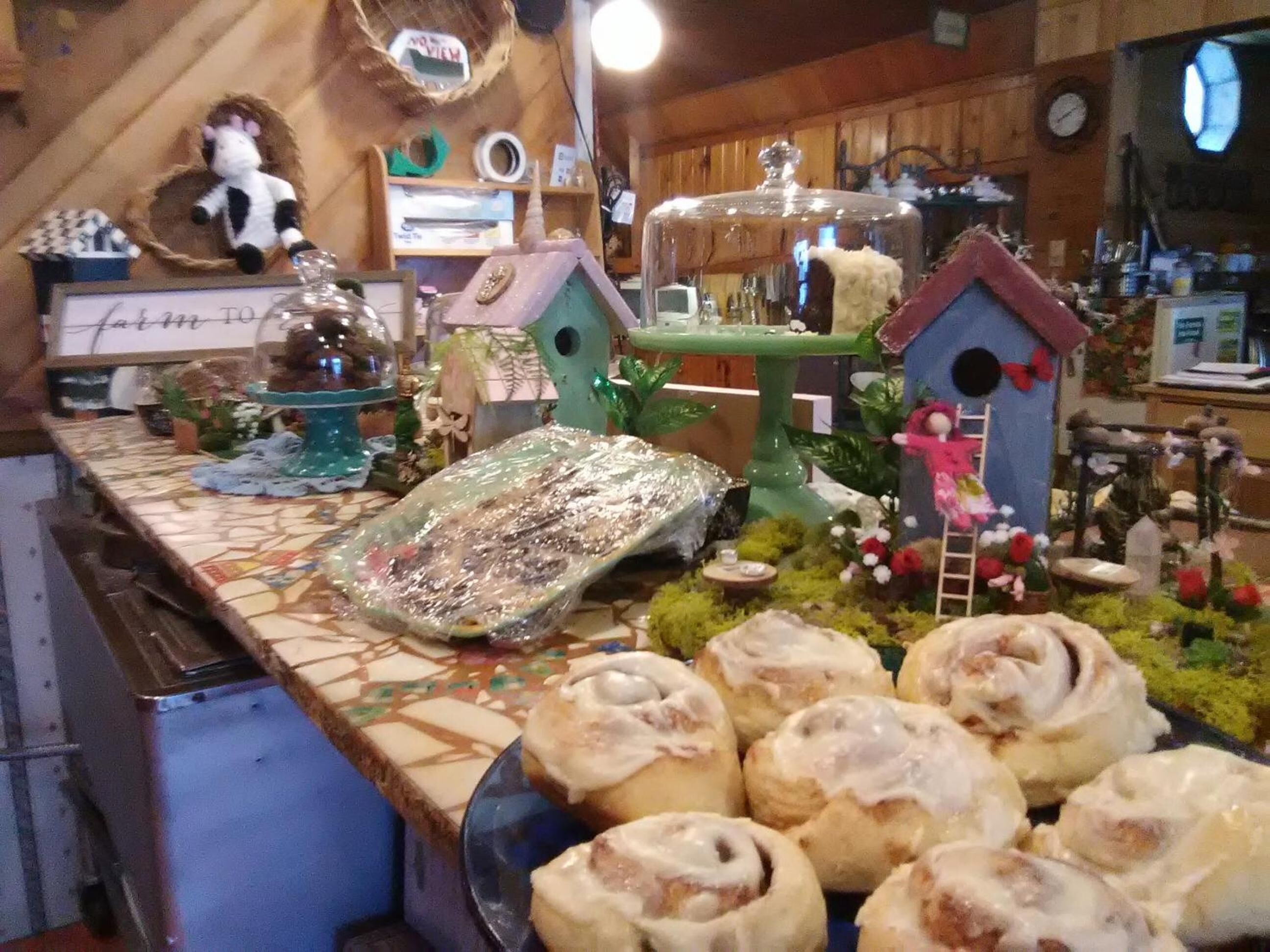 A kitchen counter with various items including a decorative birdhouse, a small figurine, and a plate of pastries.