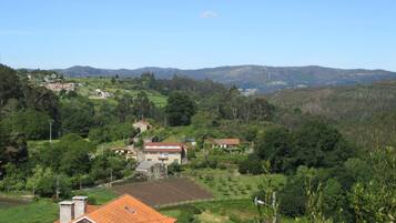 A rural landscape with houses, green fields, and hills in the background.