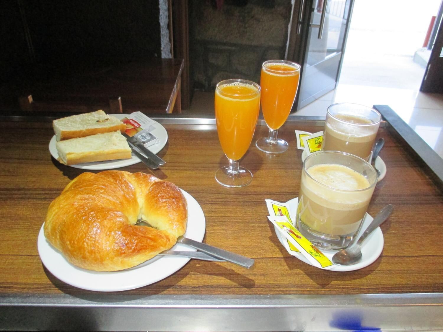 A breakfast tray with croissant, orange juice, and coffee.