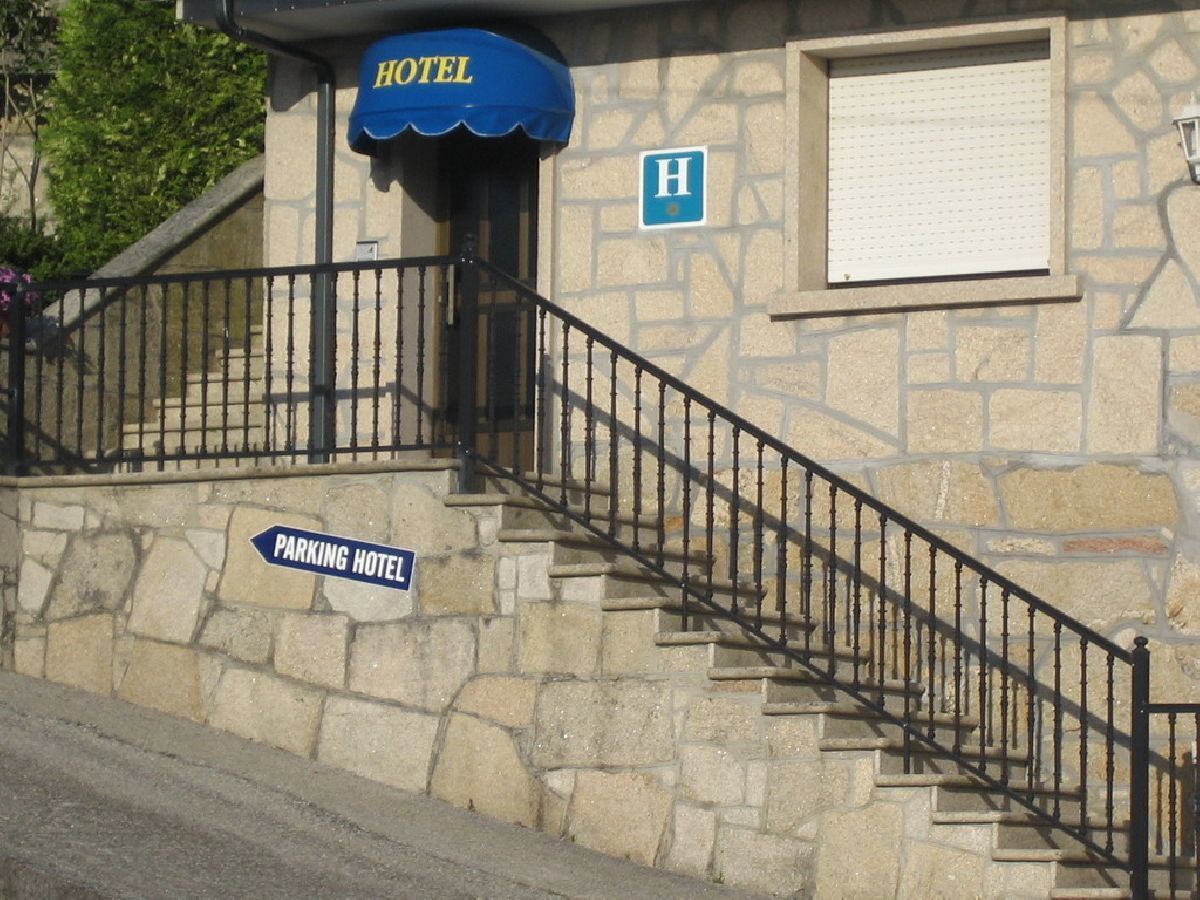 Un bâtiment en pierre avec un auvent bleu sur lequel on peut lire l’inscription « HÔTEL » et un panneau indiquant « PARCING HÔTEL ».