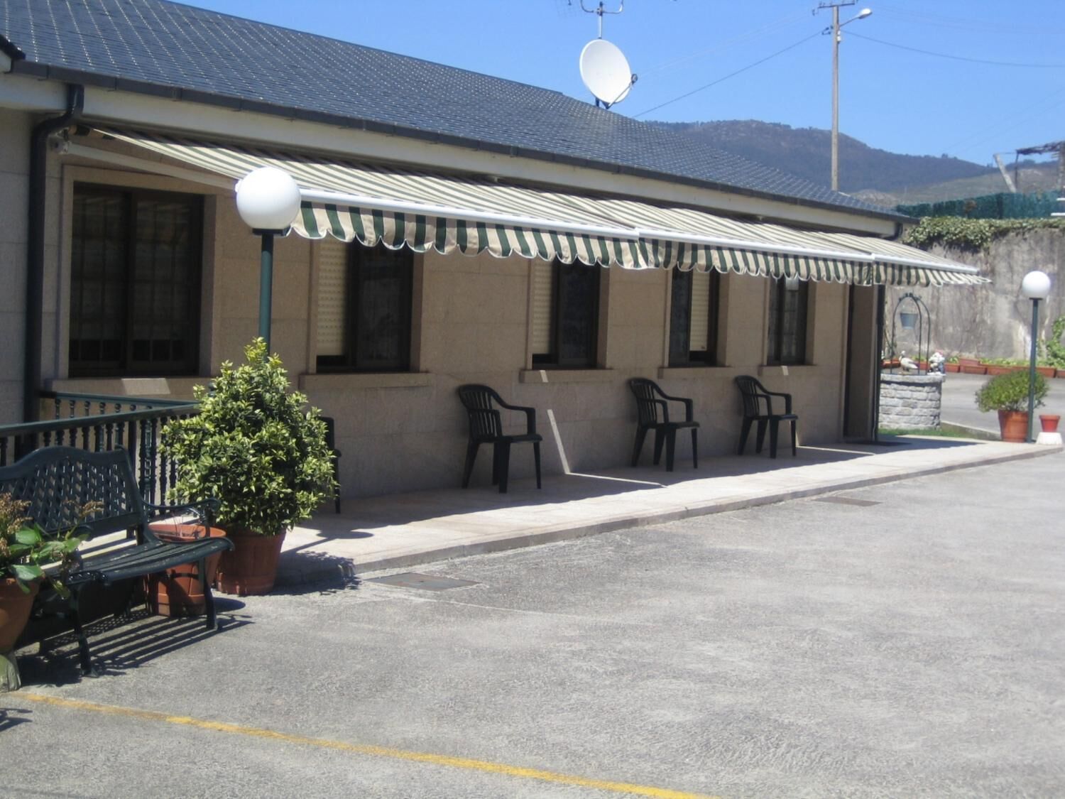 Un bâtiment doté d’un patio couvert, d’un espace extérieur aménagé pour s’asseoir et d’une antenne parabolique.