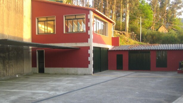 A red building with multiple windows and a flat roof. - Hotel Chola (Cerdedo-Cotobade)
