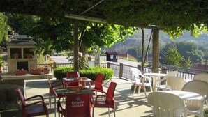 An outdoor patio area with tables and chairs, a small building with a solar panel, and a view of the surrounding landscape. - Hotel Chola (Cerdedo-Cotobade)