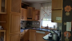 A kitchen with wooden cabinets, a dishwasher, and a kettle. - Aurora Premium Home (Gyor)