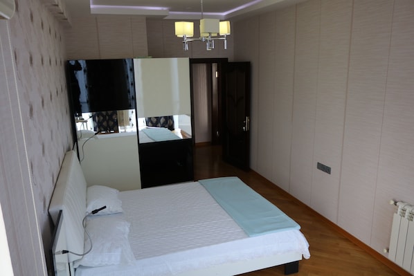 Een slaapkamer met een bed, spiegel, kast en radiator.