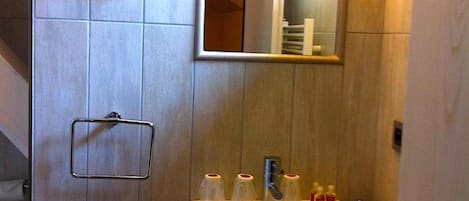 Un baño con lavamanos, espejo y toallero.
