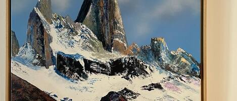 Un cuadro enmarco de un paisaje montañoso con picos nevados y cielo despejado.