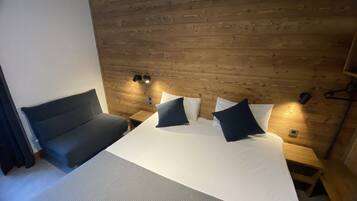 Une chambre à coucher avec un lit, un canapé, des murs en bois et des lampes fixées au mur.