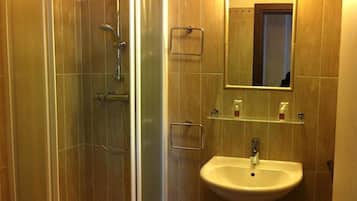 Un baño con ducha de vidrio, lavamanos y espejo sobre él.