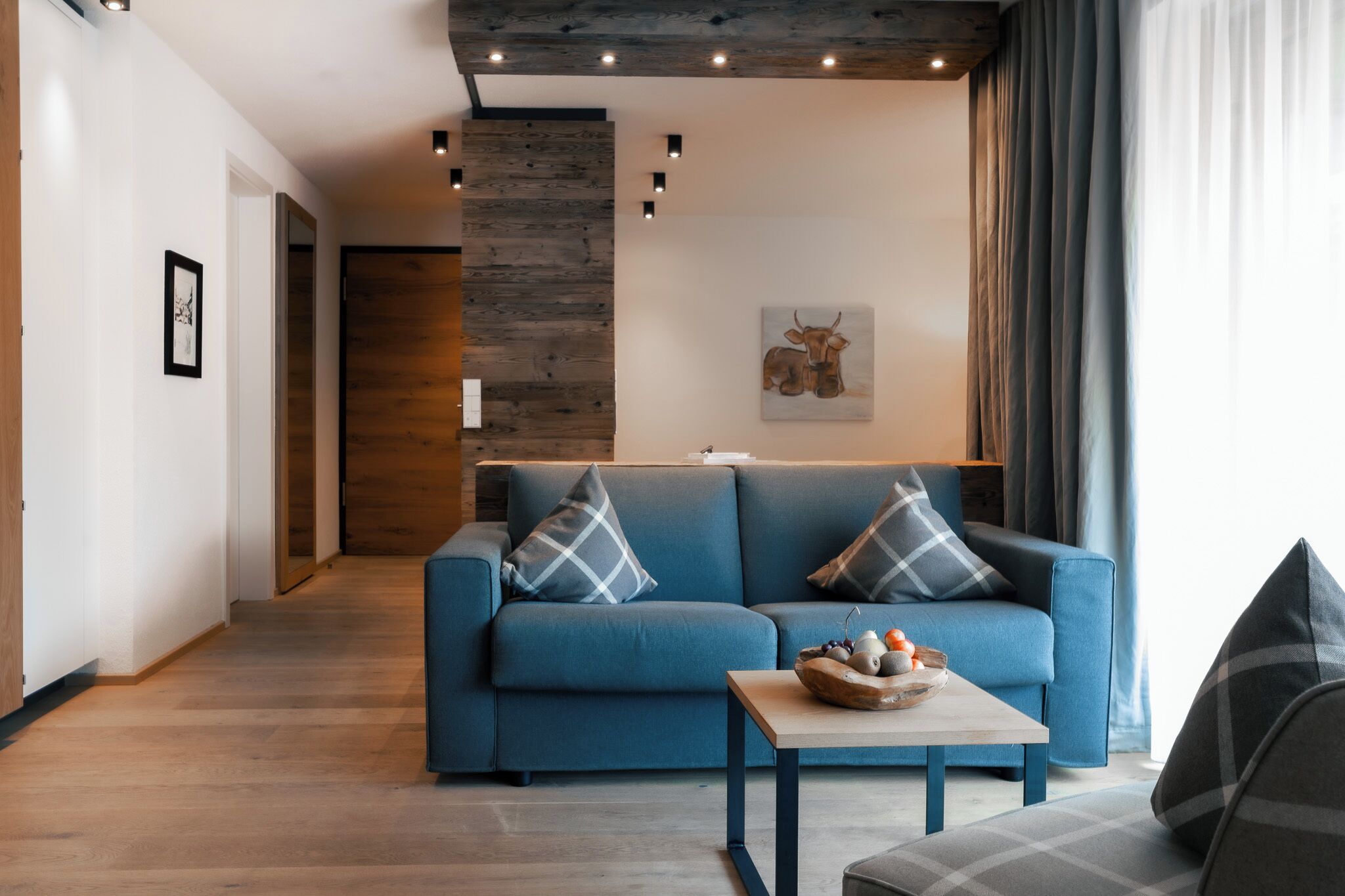 A modern living room with a blue sofa, a coffee table, and a wooden accent wall.