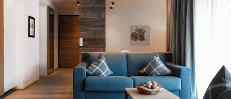 A modern living room with a blue sofa, a coffee table, and a wooden accent wall.