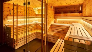 Una sauna con bancos de madera y puertas de vidrio, con un interior cálido y de madera.