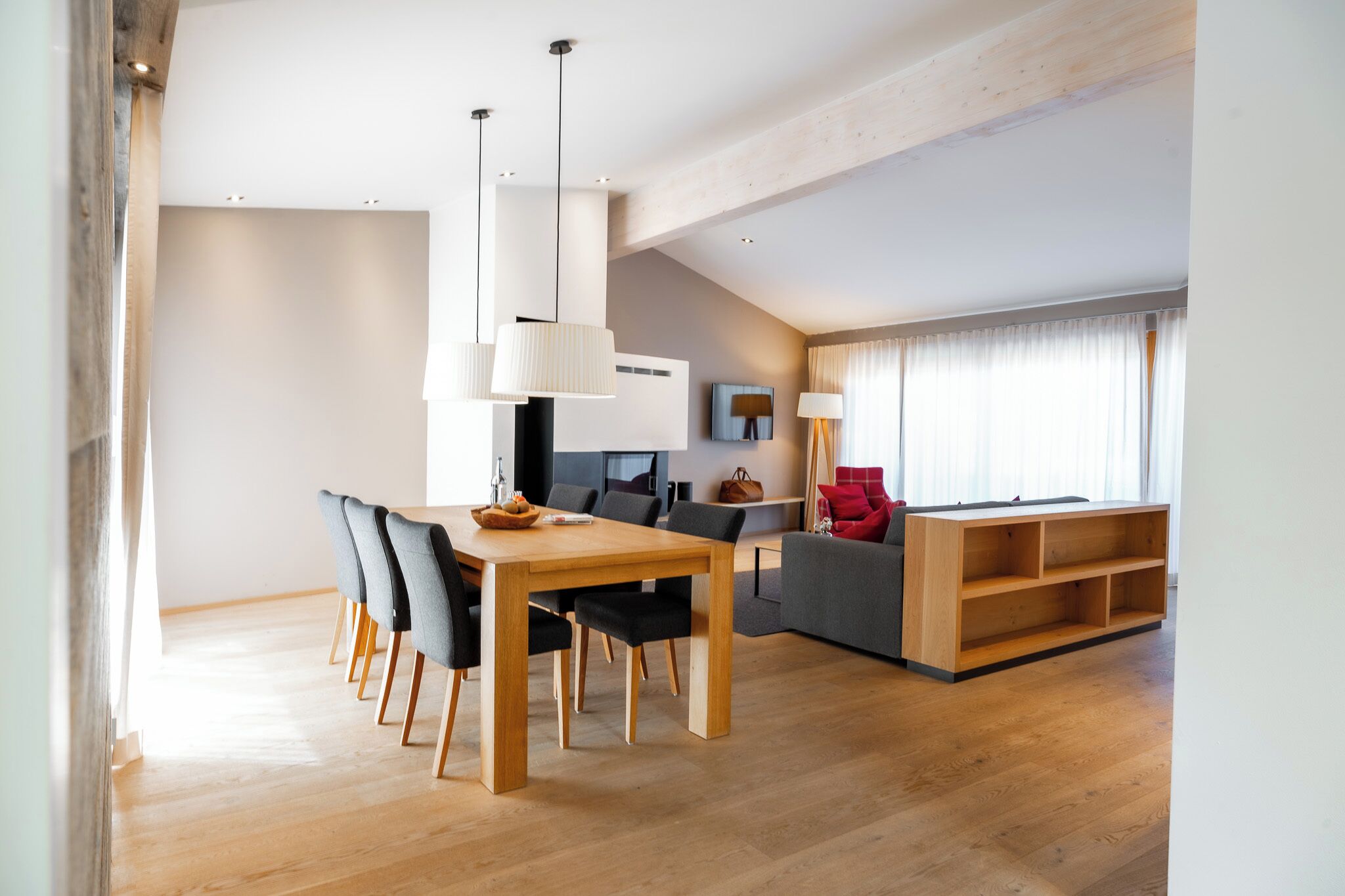 Un salon moderne avec une table à manger en bois, un canapé gris et une bibliothèque en bois.