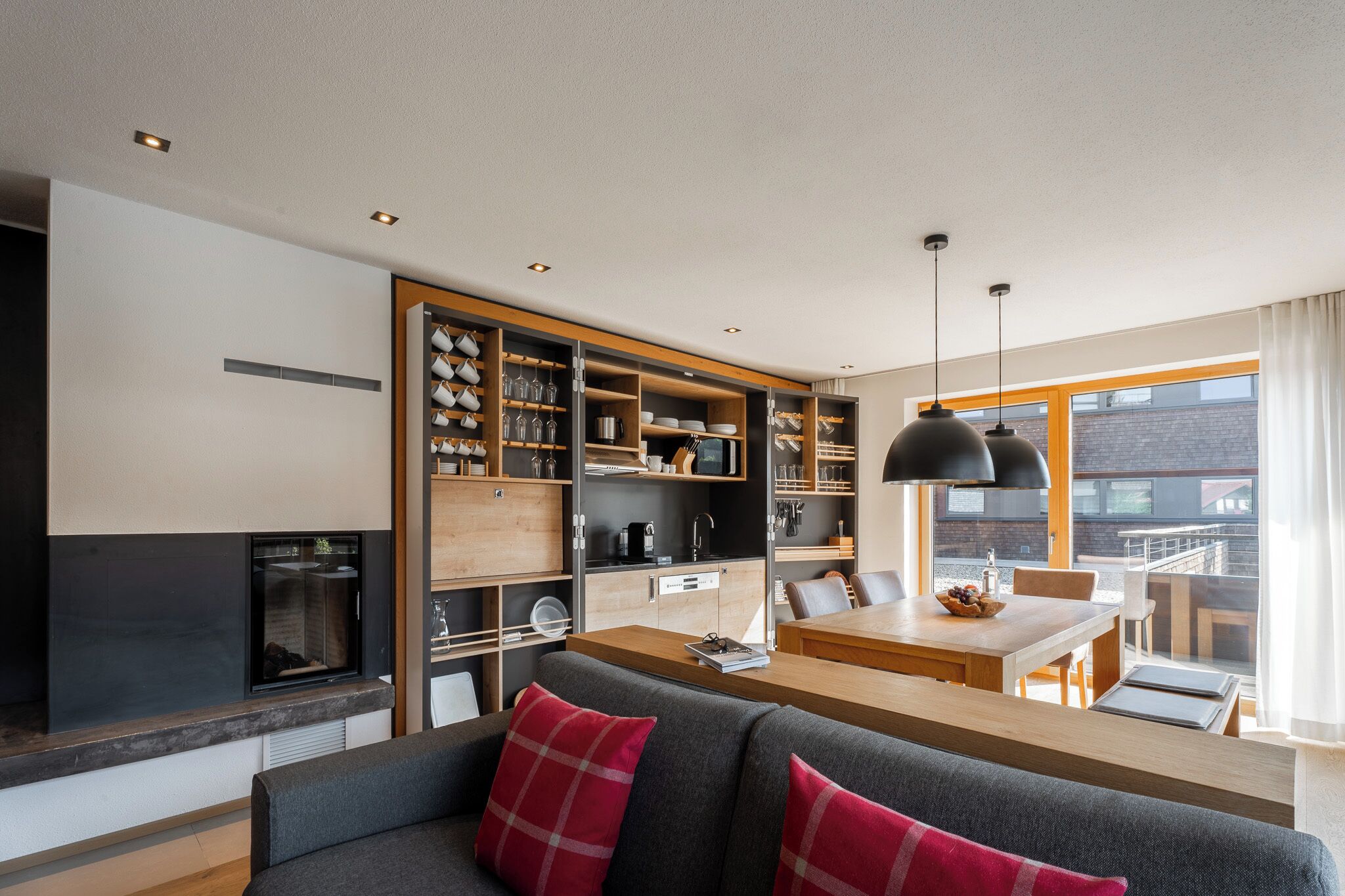 A modern kitchen with open shelving, a dining area, and a cozy seating space with a fireplace.