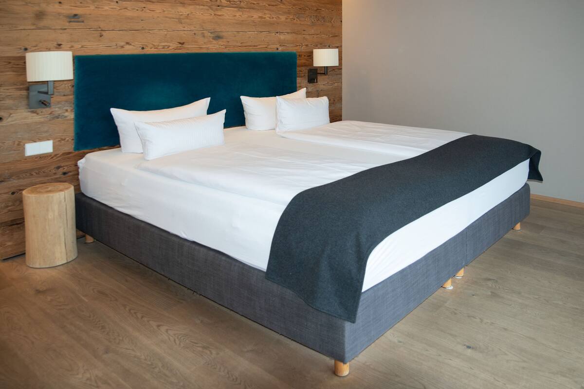 A neatly made bed with a dark headboard, white bedding, and two bedside lamps.