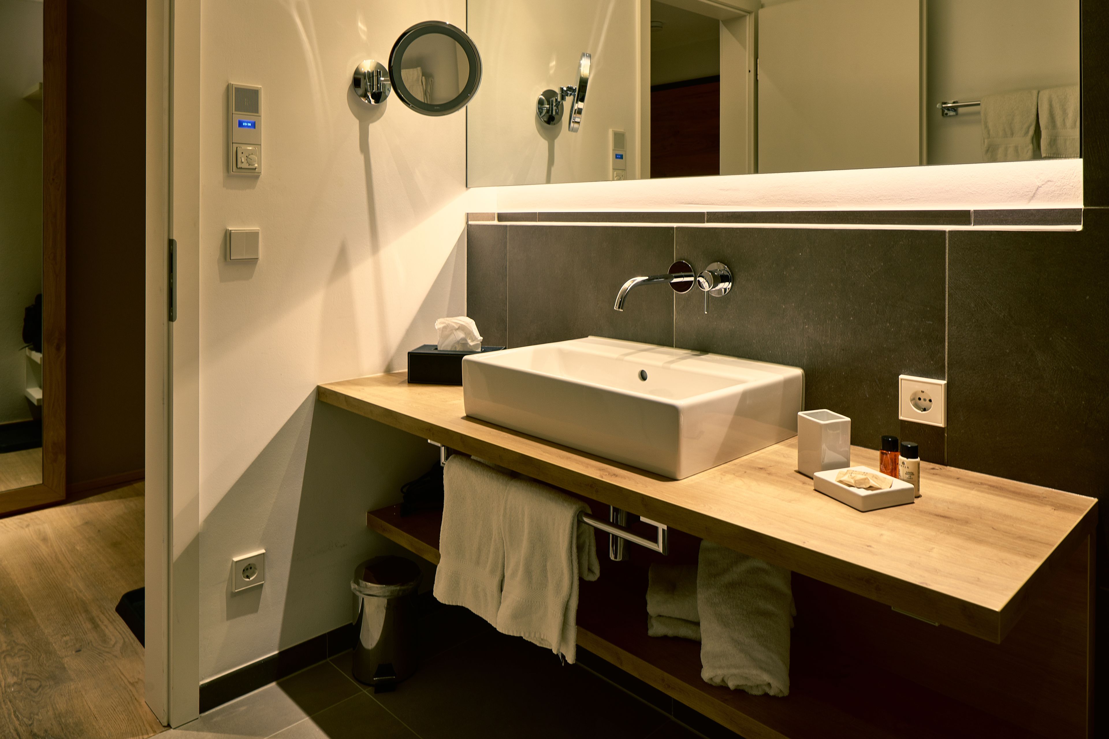 A modern bathroom with a large sink, a mirror, and a towel rack.