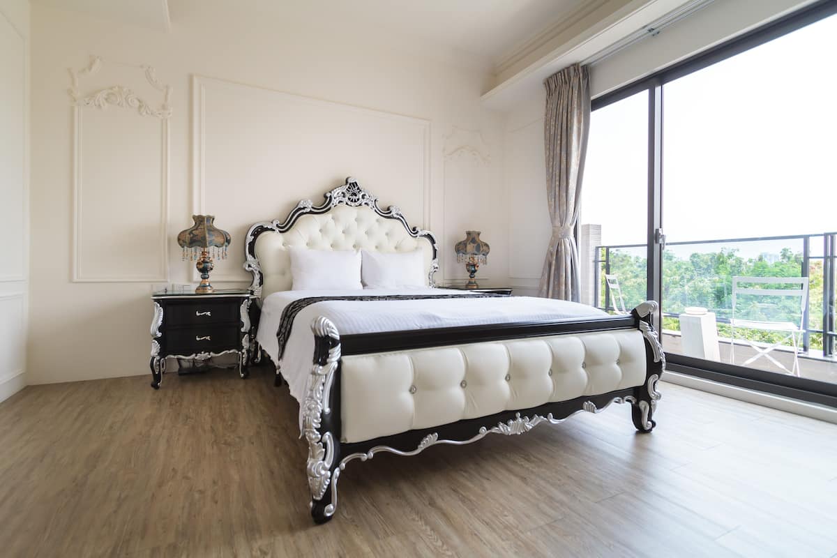 A bedroom with a large bed, two nightstands, and a view of a balcony.