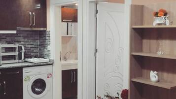 A compact kitchen with a washing machine, a microwave, and a sink.