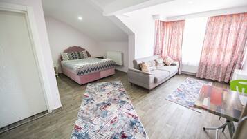 Une chambre moderne avec un lit, un canapé, une table à manger et une grande fenêtre avec des rideaux.