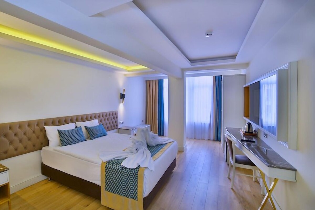 A hotel room with a large bed, bedside tables, a desk, and a mirror.