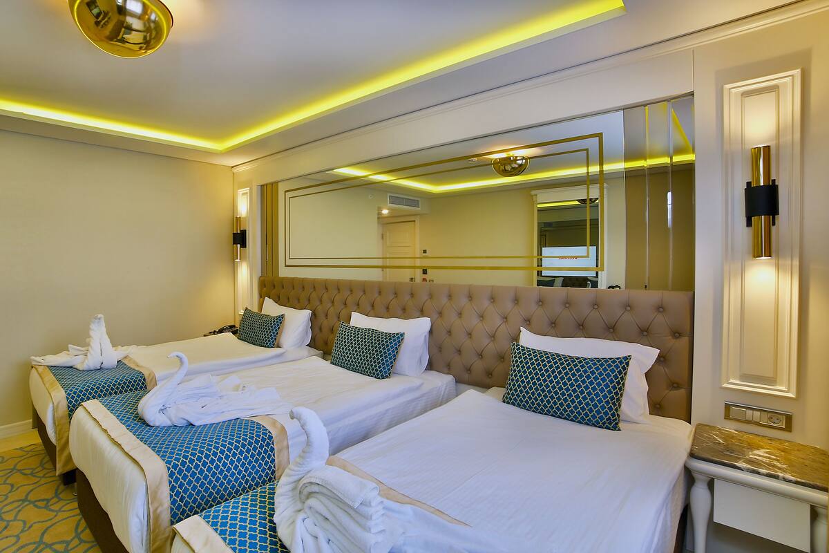 Habitación de hotel con dos camas, un espejo grande y una lámpara de techo moderna.