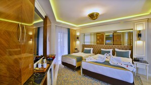 A hotel room with two beds, a sitting area with a desk, a mirror, and a minibar. - Beethoven Premium Hotel (Istanbul)
